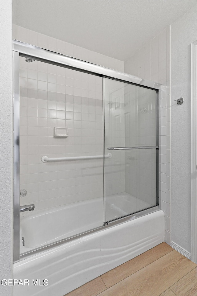 6140 Los Robles Dr, El Paso, TX 79912 - bathroom with enclosed tub / shower combo, wood finished floors, and a textured wall