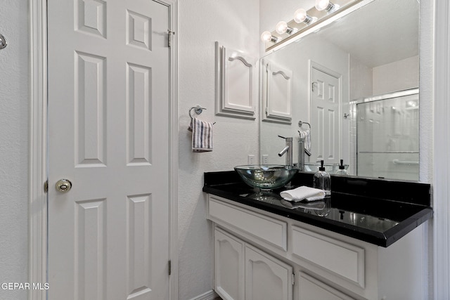 6140 Los Robles Dr, El Paso, TX 79912 - full bathroom featuring vanity, an enclosed shower, and a textured wall