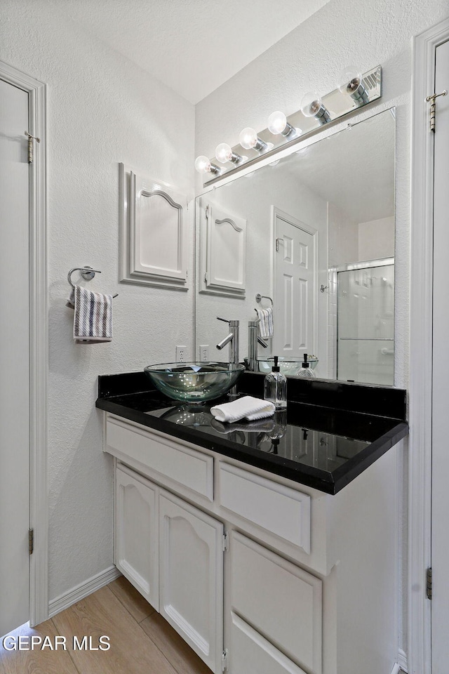 6140 Los Robles Dr, El Paso, TX 79912 - bathroom with vanity, a stall shower, and wood finished floors
