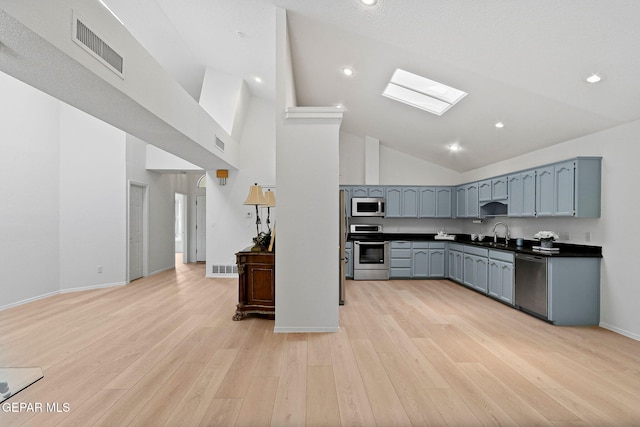 6140 Los Robles Dr, El Paso, TX 79912 - kitchen with appliances with stainless steel finishes, a skylight, high vaulted ceiling, dark countertops, and light wood finished floors