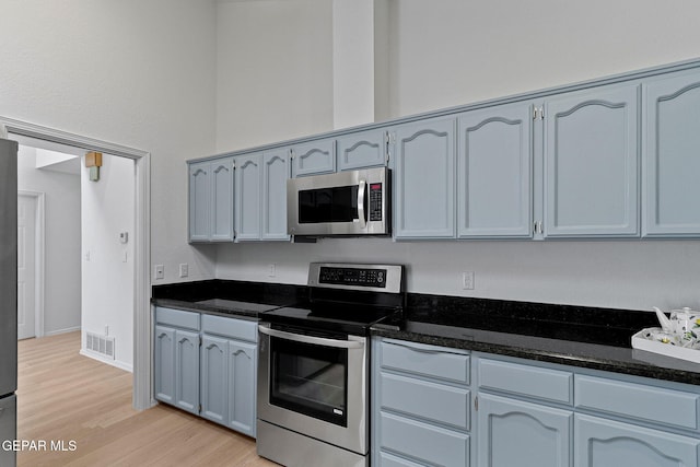 6140 Los Robles Dr, El Paso, TX 79912 - kitchen featuring stainless steel appliances, light wood-style flooring, and dark stone counters