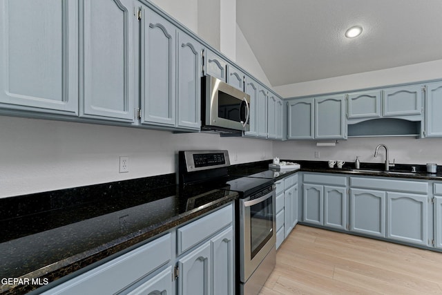 6140 Los Robles Dr, El Paso, TX 79912 - kitchen featuring appliances with stainless steel finishes, lofted ceiling, light wood-type flooring, dark stone countertops, and recessed lighting