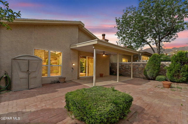 6140 Los Robles Dr, El Paso, TX 79912 - back of property at dusk featuring stucco siding, a patio area, a ceiling fan, and a chimney
