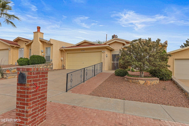 6140 Los Robles Dr, El Paso, TX 79912 - view of front facade with stucco siding, driveway, a garage, and a chimney