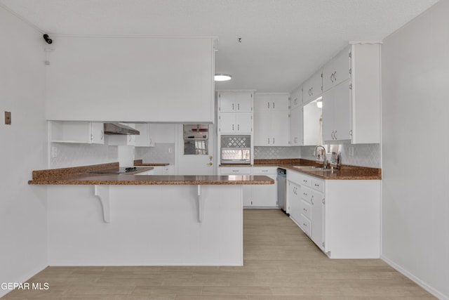 10125 Castletown Dr, El Paso, TX 79925 - kitchen featuring exhaust hood, a peninsula, white cabinets, backsplash, and light wood-style floors
