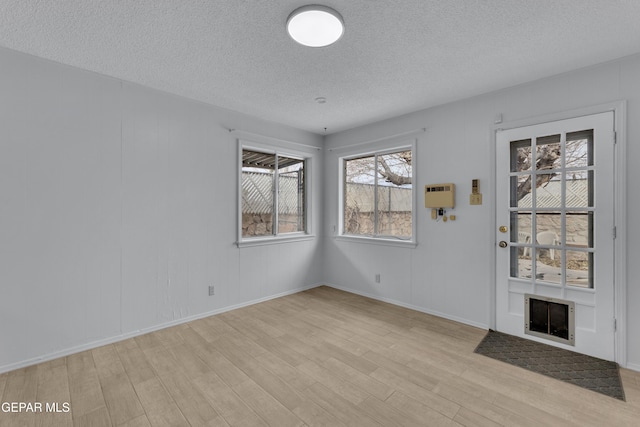 10125 Castletown Dr, El Paso, TX 79925 - entrance foyer featuring light wood-style flooring, a textured ceiling, a fireplace with flush hearth, and baseboards