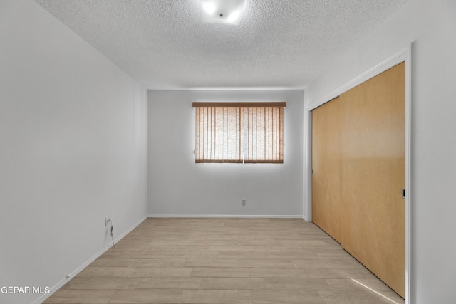10125 Castletown Dr, El Paso, TX 79925 - unfurnished bedroom featuring a textured ceiling, light wood-type flooring, a closet, and baseboards