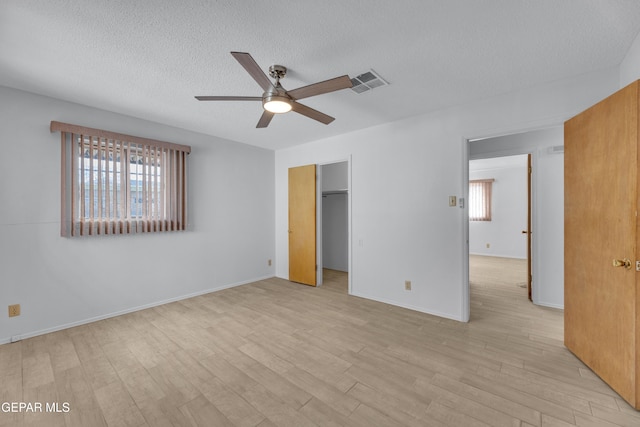 10125 Castletown Dr, El Paso, TX 79925 - unfurnished bedroom featuring a textured ceiling, light wood finished floors, a spacious closet, ceiling fan, and baseboards
