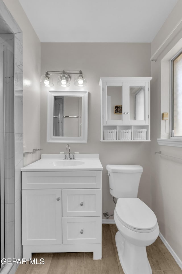 10125 Castletown Dr, El Paso, TX 79925 - bathroom with toilet, wood finished floors, vanity, and baseboards