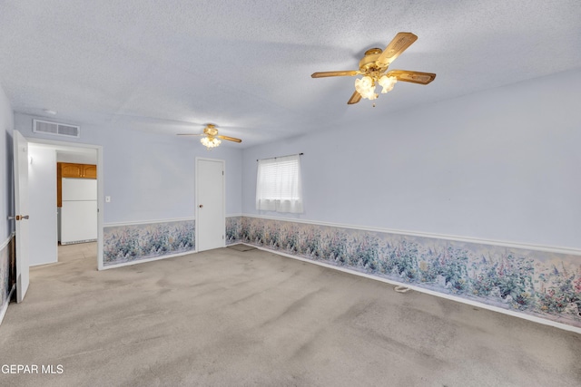 spare room with a ceiling fan, a textured ceiling, and light colored carpet