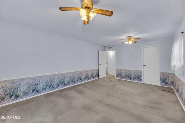 carpeted empty room featuring ceiling fan and a textured ceiling