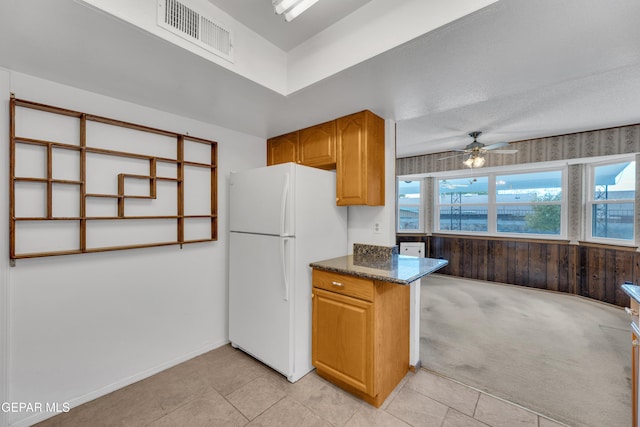 kitchen featuring freestanding refrigerator, a ceiling fan, light tile patterned floors, and dark stone counters