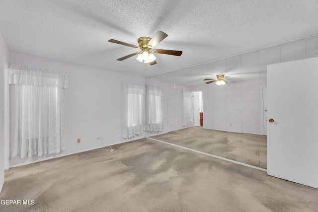 carpeted spare room featuring a ceiling fan and a textured ceiling