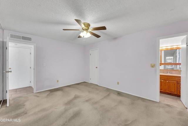 unfurnished bedroom with light carpet, ensuite bath, baseboards, a textured ceiling, and a ceiling fan