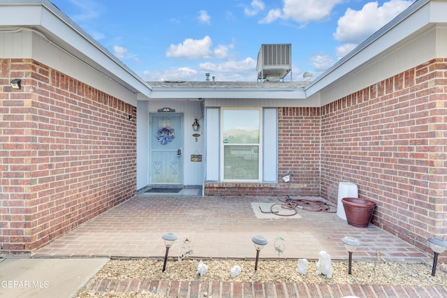 view of exterior entry with brick siding and central air condition unit