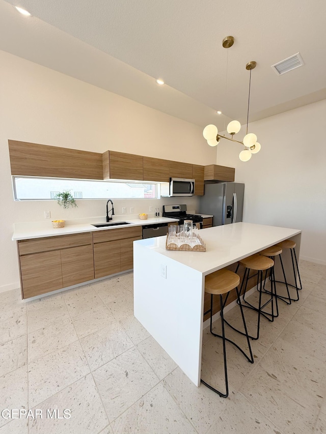 15101 Steer Dr, El Paso, TX 79938 - kitchen with appliances with stainless steel finishes, a sink, brown cabinetry, light countertops, and a kitchen breakfast bar