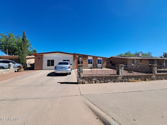 single story home featuring concrete driveway, a garage, a fenced front yard, and brick siding