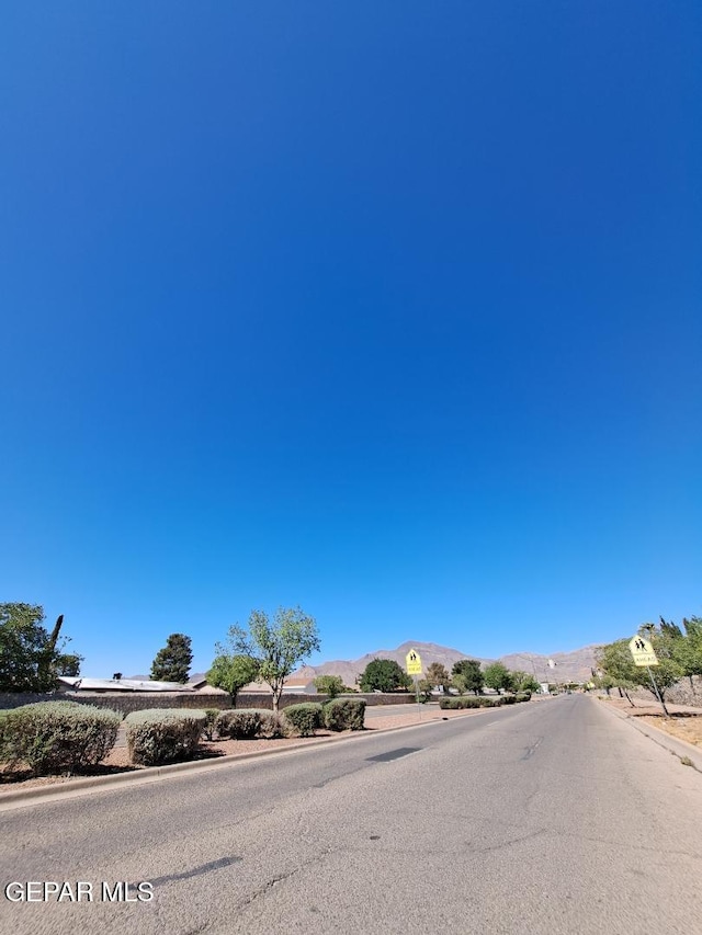 view of asphalt street featuring traffic signs and a mountain view