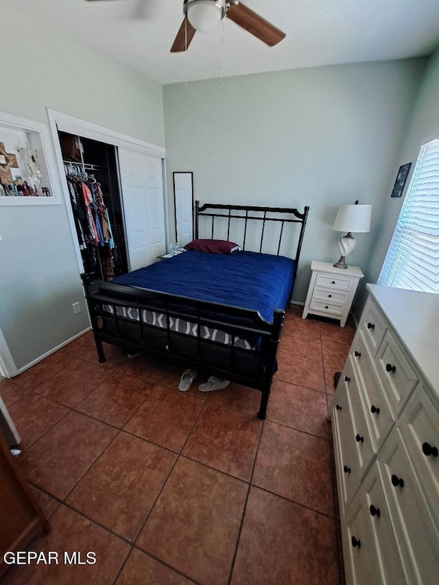 bedroom with a closet, dark tile patterned flooring, a ceiling fan, and baseboards