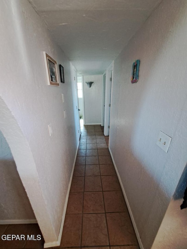 corridor with baseboards and tile patterned flooring