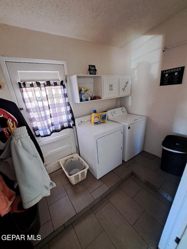 clothes washing area with washer and clothes dryer, a textured ceiling, and tile patterned flooring