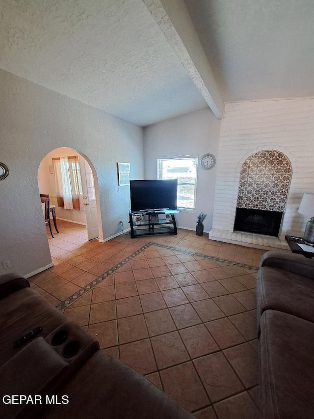 living room featuring tile patterned flooring, baseboards, arched walkways, a fireplace, and a textured ceiling