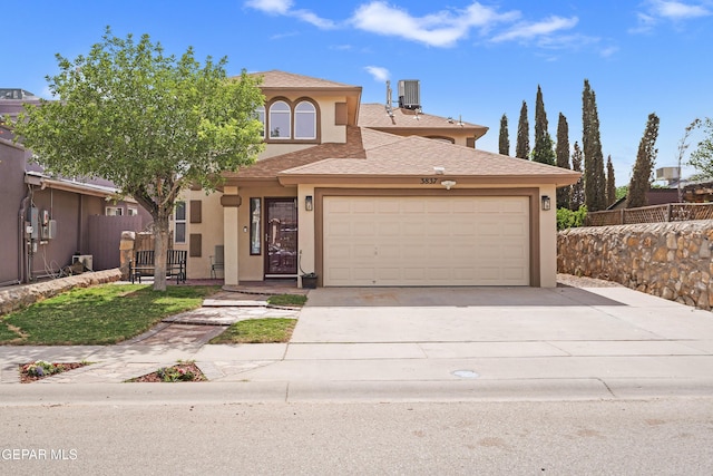 view of front facade with stucco siding, a garage, concrete driveway, and central air condition unit