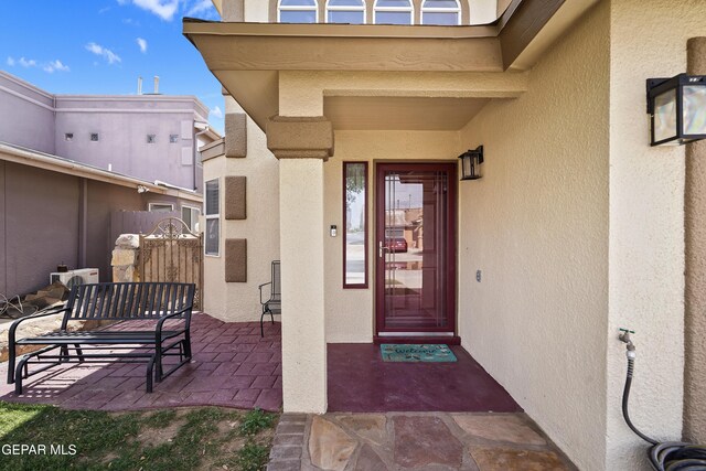view of exterior entry with stucco siding and a patio area
