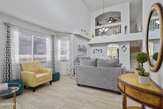 living area with a high ceiling, a chandelier, arched walkways, and a ceiling fan