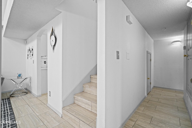 stairs featuring a textured ceiling and wood tiled floors