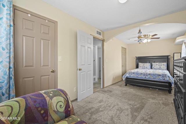 carpeted bedroom with arched walkways, a ceiling fan, and baseboards
