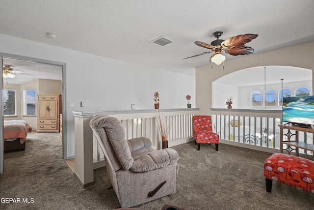 living area with carpet floors, a ceiling fan, healthy amount of natural light, and a textured ceiling