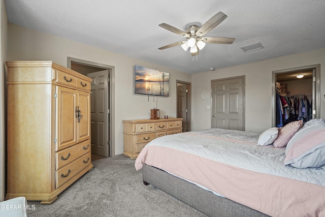 bedroom featuring light carpet, a walk in closet, a closet, and a ceiling fan