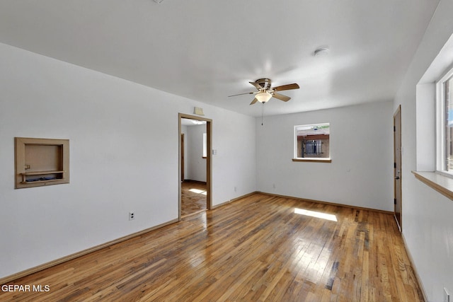 spare room with a ceiling fan, hardwood / wood-style floors, and baseboards