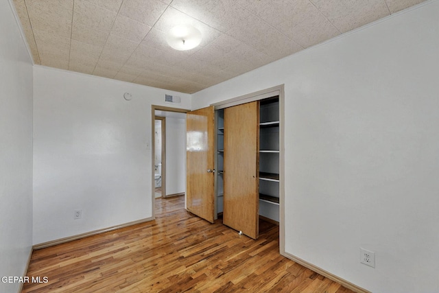 unfurnished bedroom with wood finished floors, a closet, and baseboards
