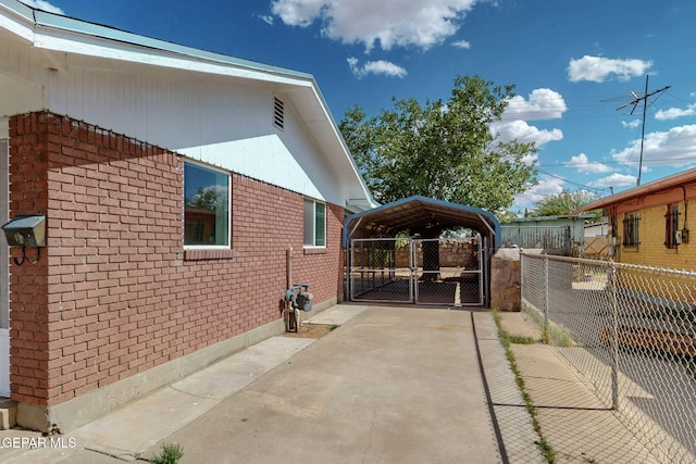 view of side of home with brick siding, a detached carport, fence, and a gate