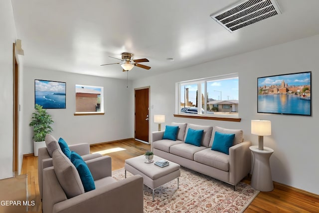 living area with ceiling fan, light wood finished floors, and baseboards