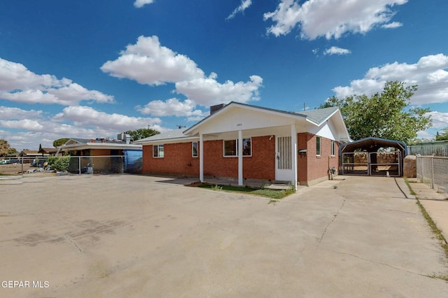 view of front of home featuring a carport, fence, brick siding, and concrete driveway