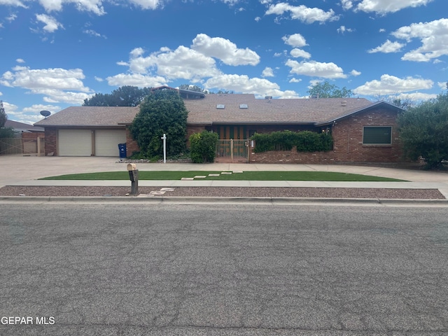 view of front of home featuring concrete driveway, fence, an attached garage, and brick siding