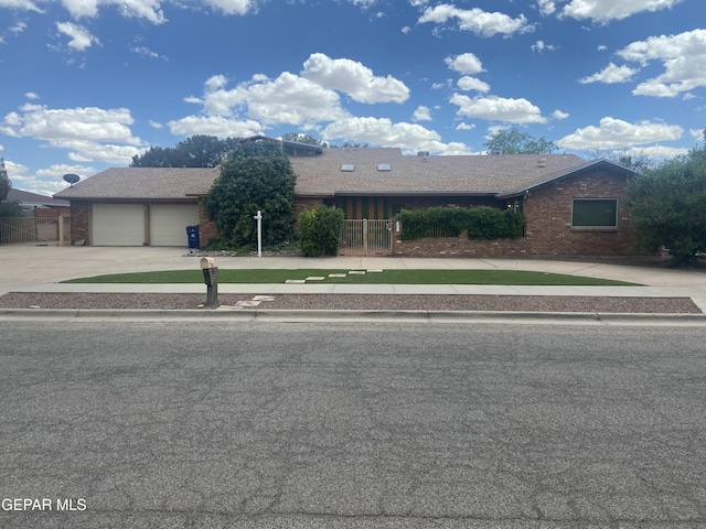 ranch-style house featuring driveway, brick siding, a garage, and fence