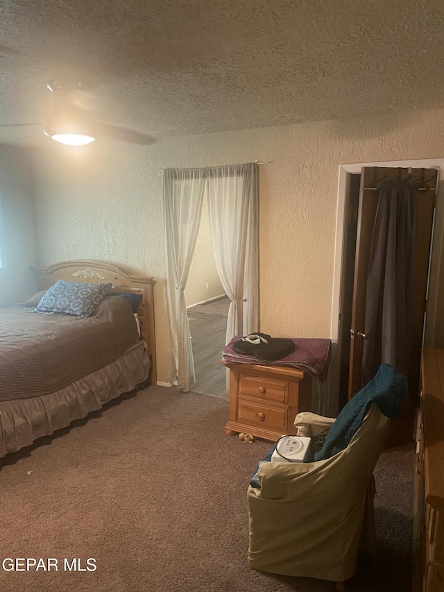 carpeted bedroom with a textured wall and a textured ceiling