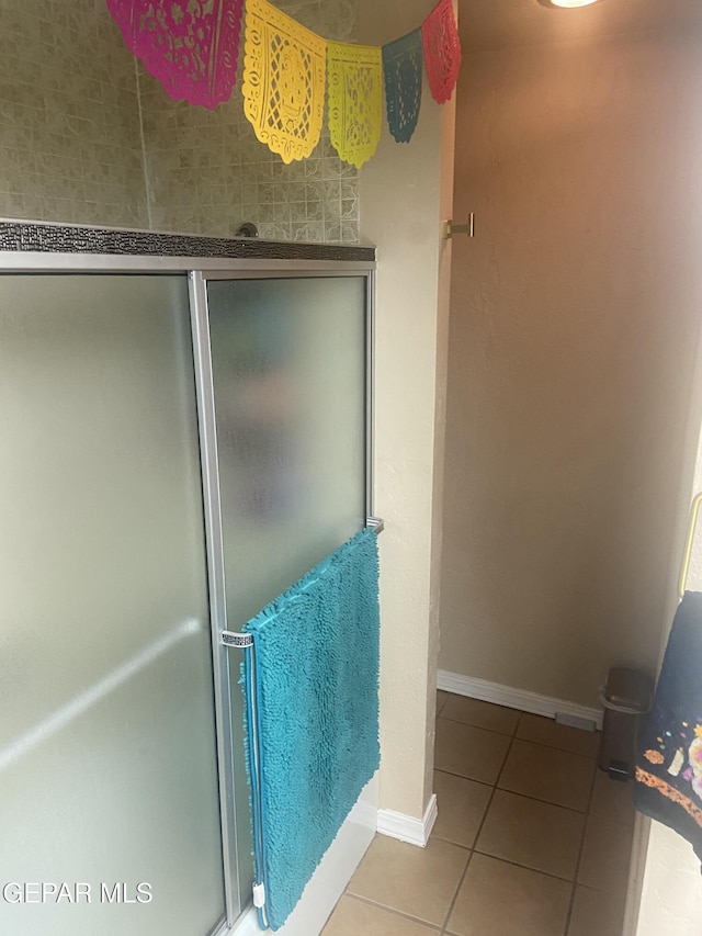 full bathroom with tile patterned flooring, a shower with door, and baseboards