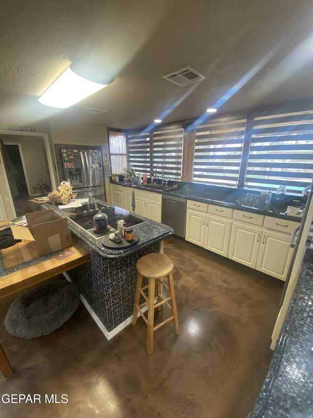 kitchen with dishwasher, dark countertops, a sink, and white cabinetry