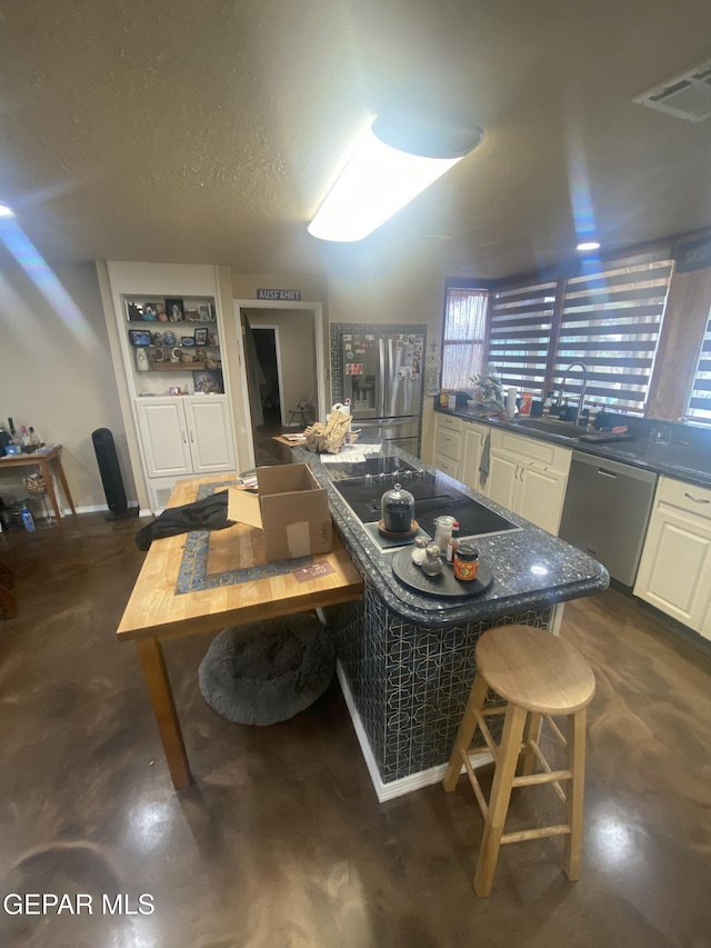 kitchen featuring appliances with stainless steel finishes, dark countertops, finished concrete floors, and white cabinets