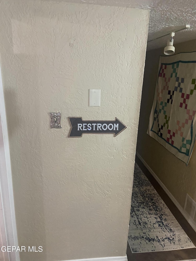detailed view of baseboards and a textured wall