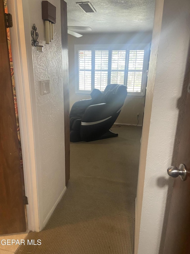 hall featuring carpet flooring, a textured wall, and a textured ceiling