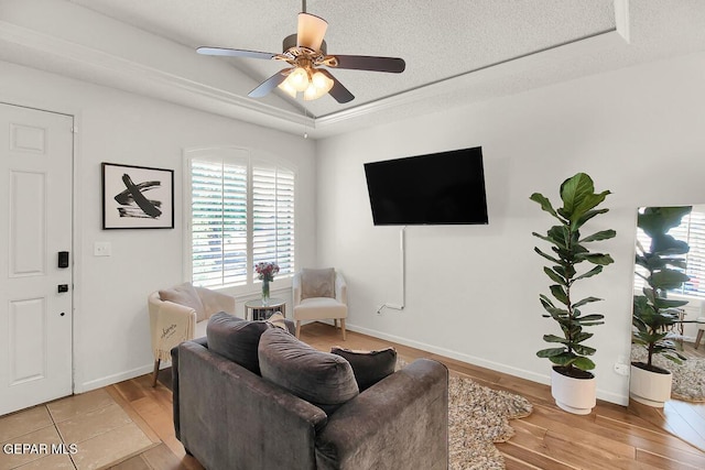 4729 Joseph Rodriguez Dr, El Paso, TX 79938 - living area featuring a tray ceiling, light wood-style floors, a ceiling fan, a textured ceiling, and baseboards