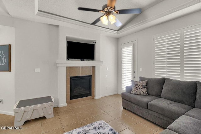 4729 Joseph Rodriguez Dr, El Paso, TX 79938 - living room featuring a ceiling fan, a tray ceiling, tile patterned floors, a tiled fireplace, and vaulted ceiling