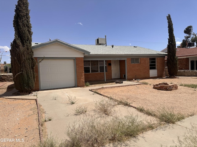 ranch-style house featuring an attached garage, driveway, brick siding, and roof with shingles