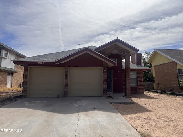 view of front of property with an attached garage, concrete driveway, brick siding, and roof with shingles
